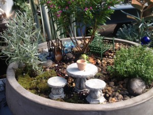 Miniature garden, gray round bow, stone table and stools, green bench, bridge, heather tree